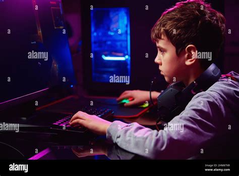 Teenager boy play computer video game in dark room, use neon colored ...