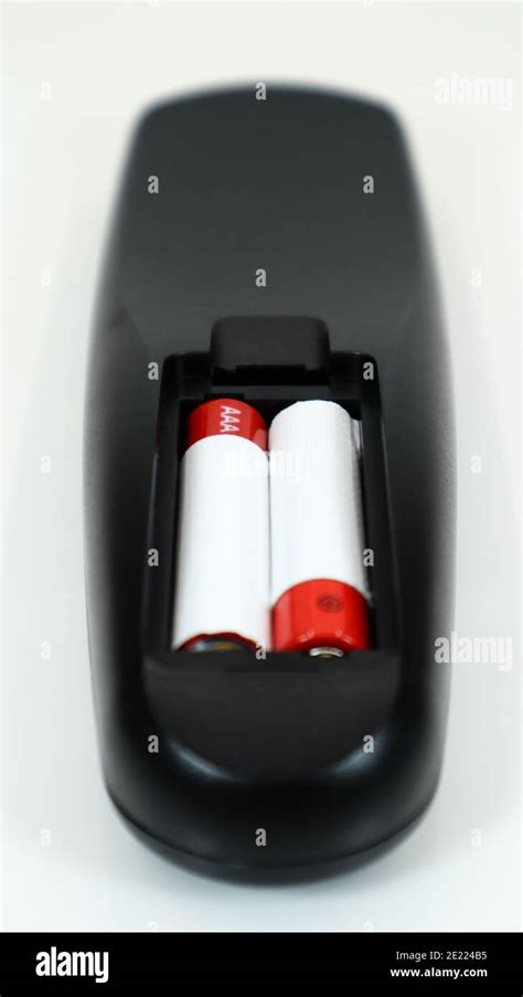 Black TV remote control with AAA alkaline batteries in red and white on ...