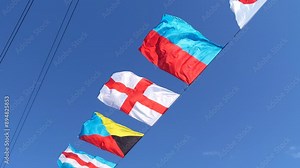 International maritime signal flags are waving on wind under blue cloudy sky