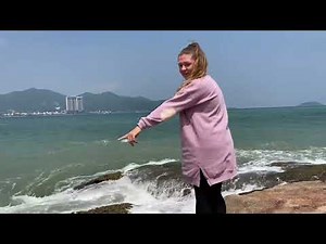 Photo shoot in wet clothes on a rock, huge waves pour over clothes. Purple sweatshirt, leggings