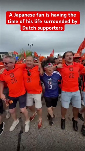 A Japanese fan is having the time of his life surrounded by Dutch supporters #Japan #Netherlands