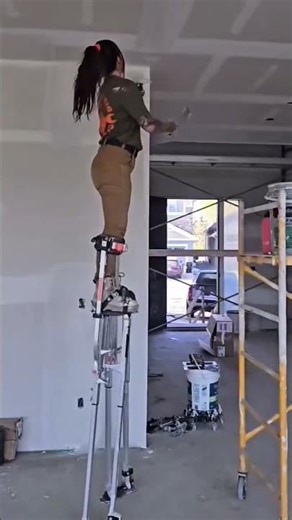 Pro Drywall Finisher Using Stilts for Ceiling Work