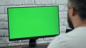 clip-1108778309-bearded-middle-aged-man-working-desktop-computer-green