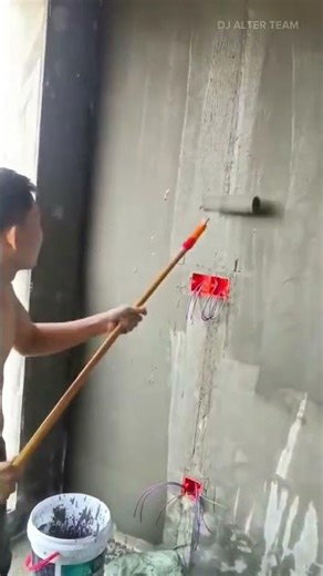 applying a grey primer coating to a concrete wall using a long handled roller for wall preparation
