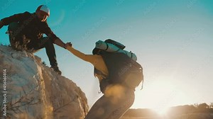 Helping Hand. Man giving hand a teammate to help her to climb the mountain. Help and assistance, hand reaching out to help friend at beautiful sunset sky. Hiking and team work concept. People helping.