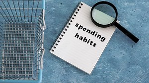 spending habits text on notepad with shopping basket and magnifying glass and payment cards, money and consumer behaviour