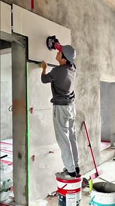 Tiler installing large tile with suction cup tool, guided by laser line