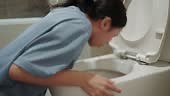 Woman vomiting in the bathroom toilet.