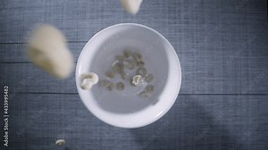 Healthy cereal breakfast falls into bowl with milk being poured in slow motion