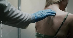 Dermatologist examining moles of female patient.