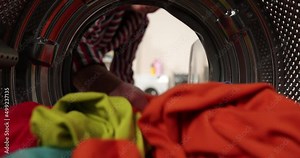 View looking from inside washing machine, man takes out laundry
