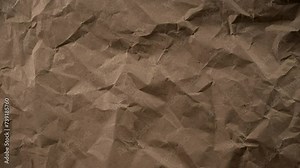 Animation of crumpled craft paper moving frame by frame. The texture of the wrinkled paper moves. Unveils an intricate pattern of folded lines and shadows, offering a visual journey through randomness