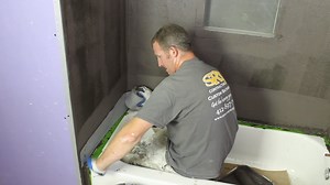 (Part 2) Waterproofing cement board with Ardex 8 9 by rolling vertically, taping off tub, applying SK Mesh at transitions, allowing to cure then rolling on second coat horizontally...note: this but was our mock-up, all tubs should be protected before using any liquid membrane or backer board...full tutorial https://www.homerepairtutor.com/how-to-waterproof-a-shower-with-ardex/ | Home Repair Tutor