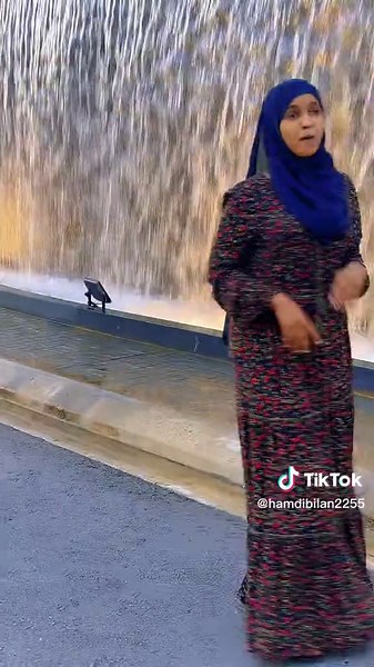 Floral Dress and Blue Headscarf by Water Fountain