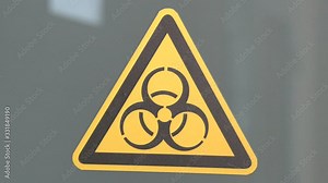 Biohazard symbol sign of biological threat alert. The sign on the door is “Caution. Biohazard (Infectious Substances)”.