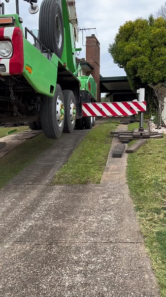 Crane Lifts Large Green Truck in Residential Area