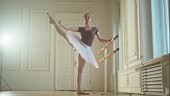 Young ballerina in tutu skirt dancing practicing ballet positions in...