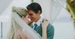 Bride and groom sharing intimate moment kissing on wedding day