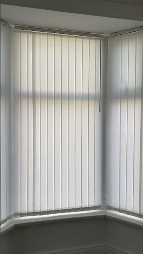 Plain white vertical blinds installed on a bay window,