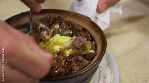 Hands mixing Hong Kong clay pot beef and egg garlic Cantonese Chiense food