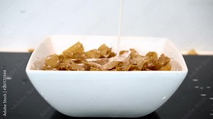 Milk pouring into a bowl with full of cereal in slow motion and zoom in effect